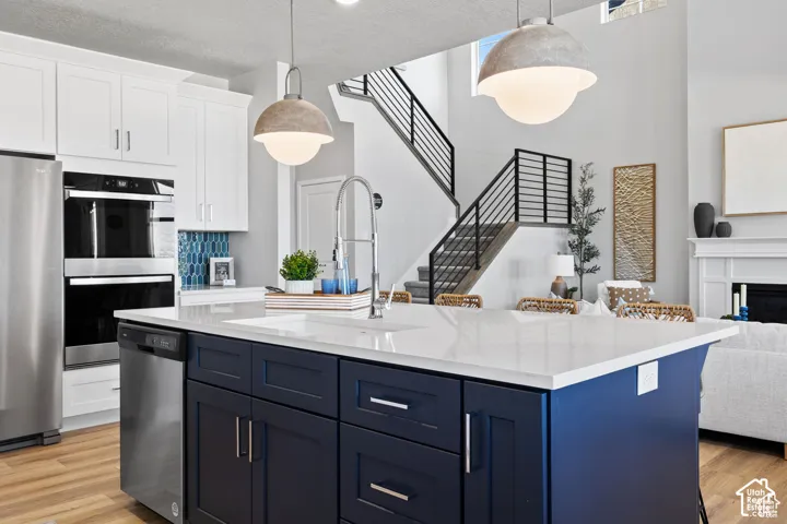 Kitchen featuring a central island with a white countertop and blue cabinetry, stainless steel appliances, and wood-finish flooring