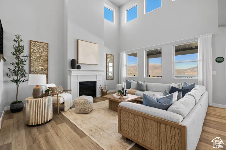 Living area featuring a two-story ceiling, a white mantel fireplace, and wood-finish flooring