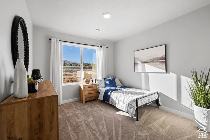 Bedroom featuring a large picture window, neutral wall paint, and textured carpet flooring
