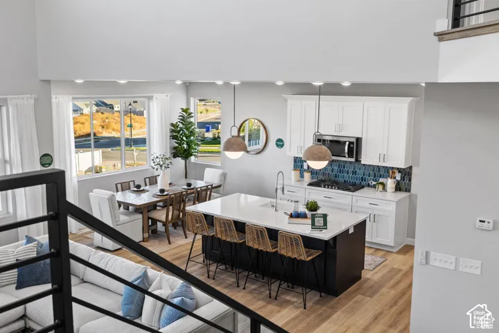 Open-concept living space featuring a double-height ceiling, wood-finish flooring, and recessed lighting