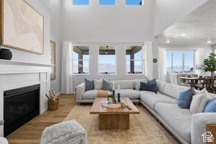 Spacious living area featuring high ceilings, a built-in fireplace with a white mantel, numerous windows, wood-finish flooring, and recessed lighting