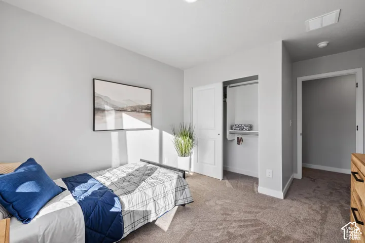 Bedroom featuring neutral gray wall paint, textured carpet flooring, and a built-in closet with white bifold doors