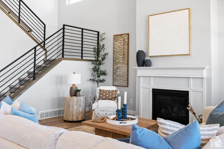 White fireplace with a detailed mantel, a black firebox, wood-finish flooring, and a staircase featuring black metal railings