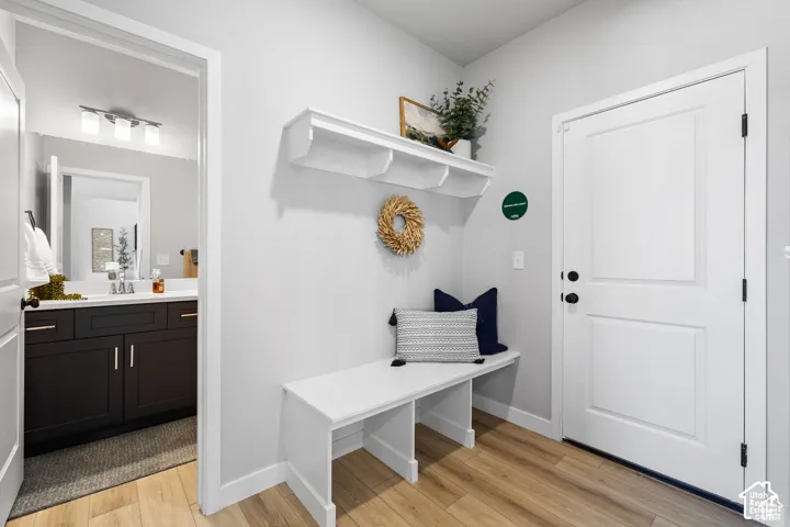 Entryway mudroom area featuring wood-finish flooring, a built-in white bench, and a white wall shelf