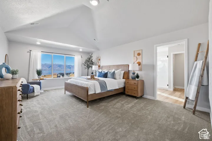 Spacious bedroom featuring vaulted ceilings and a large picture window with mountain and water scenery