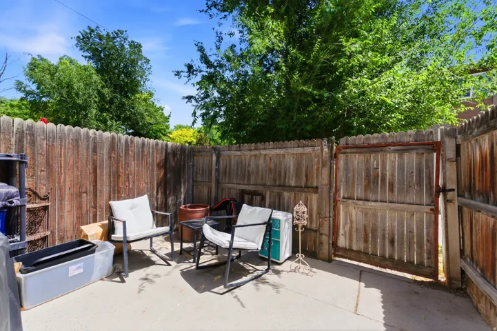 Private patio space featuring a solid wood fence, concrete flooring, and mature perimeter trees