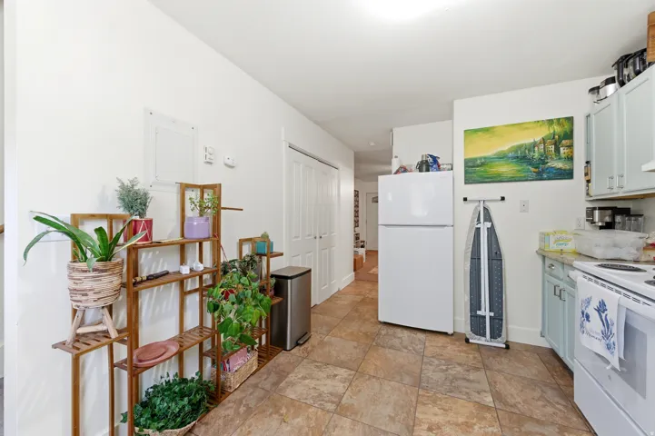 Kitchen area featuring tile flooring, white appliances, light blue cabinetry, and a light-toned countertop