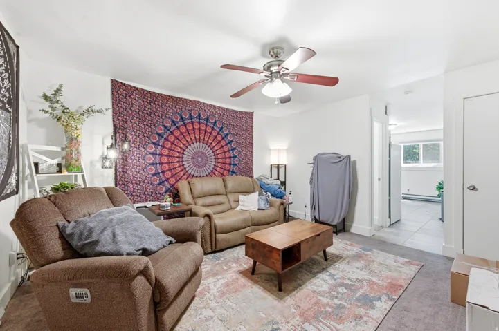 Living area featuring a ceiling fan with integrated lighting and carpet flooring
