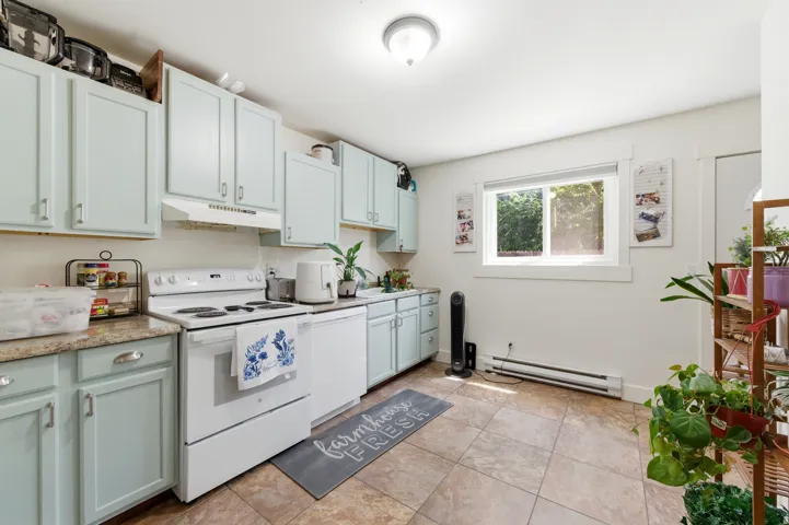 Kitchen featuring light green cabinetry, white appliances, countertops, and tiled flooring