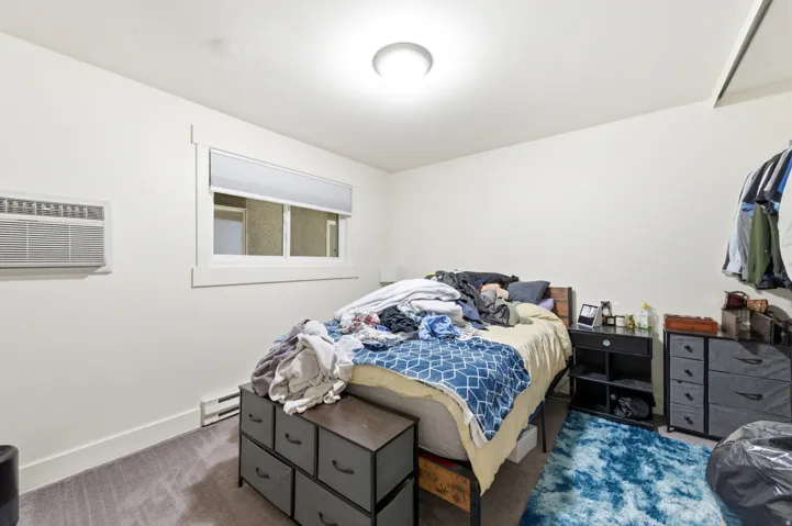 Bedroom featuring wall-to-wall carpeting, white painted walls, and a window with white trim