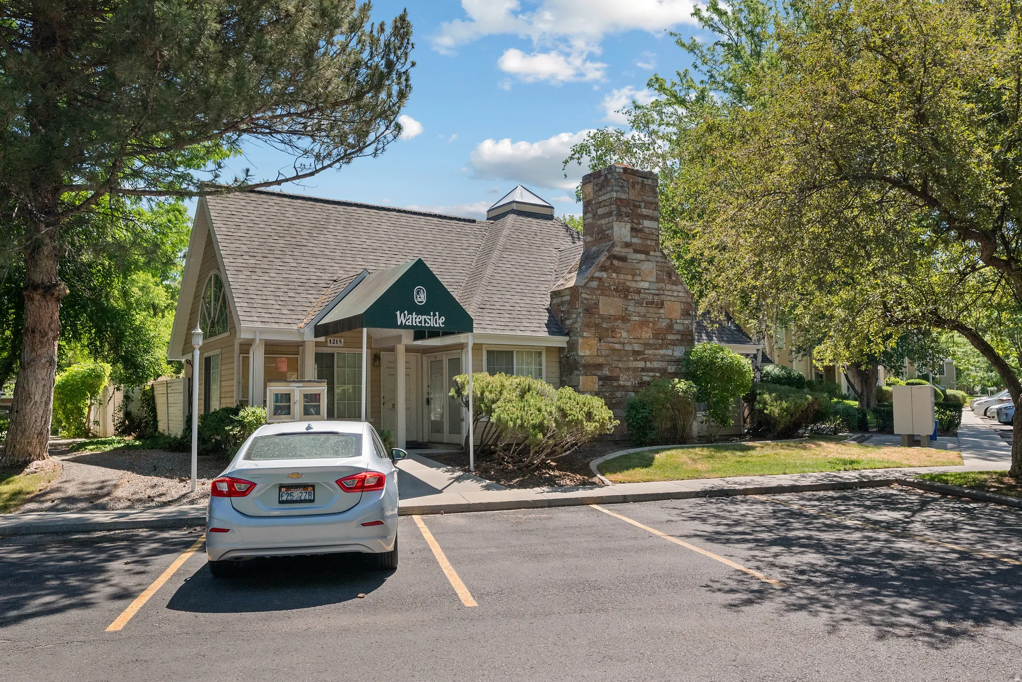 Gable roofline structure featuring a decorative arched window, a stone-clad chimney, and a covered entrance with an awning
