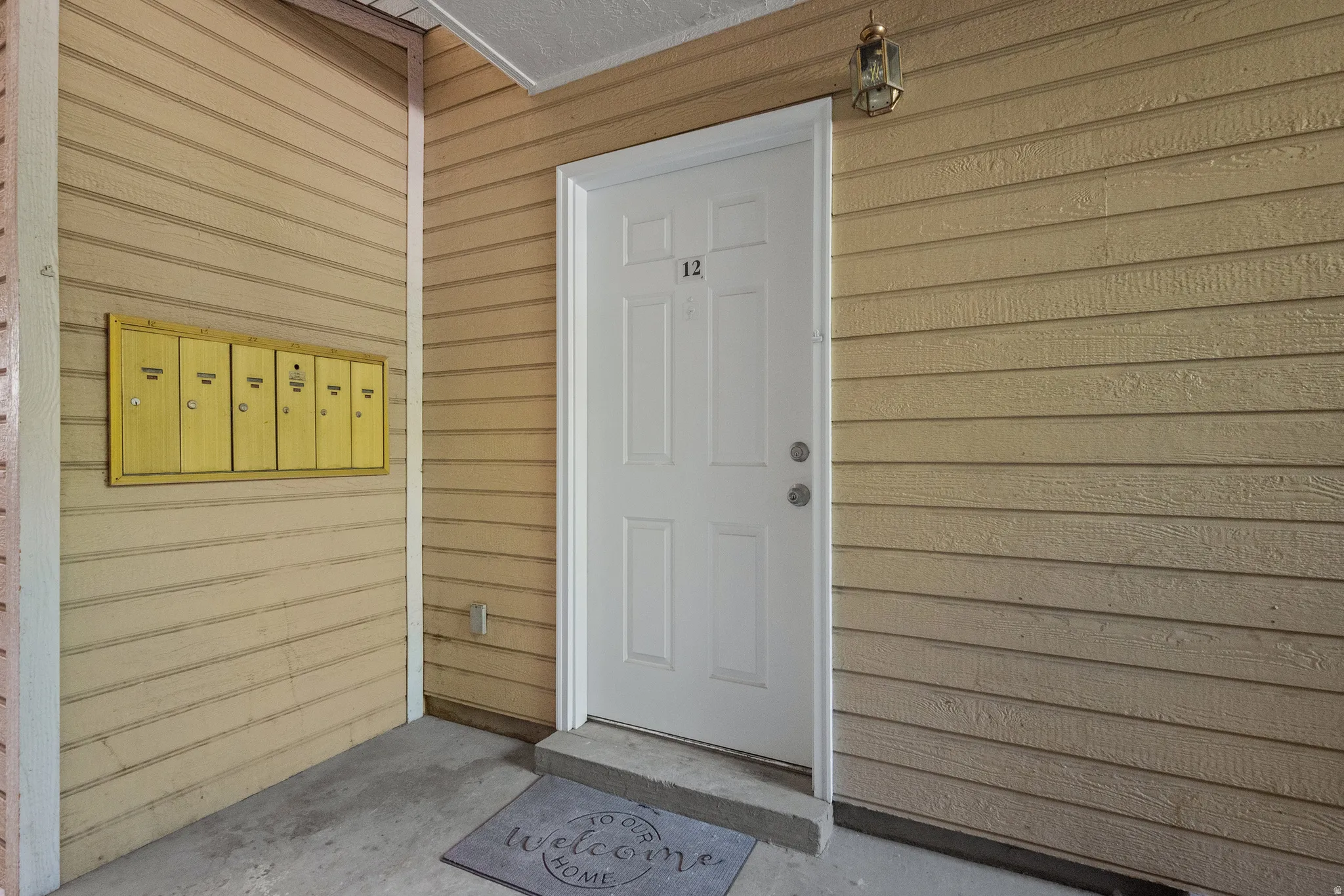 Entryway featuring horizontal siding, a white front door with panel detailing, and an overhead light fixture