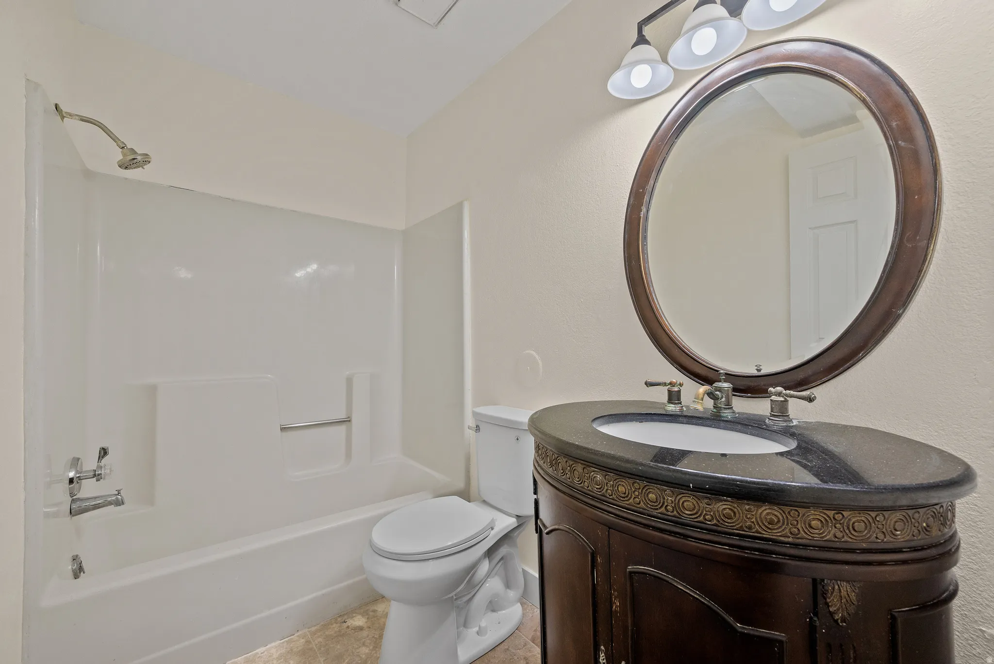 Bathroom featuring a dark wood vanity with an oval basin, a dark countertop, and an oval framed mirror
