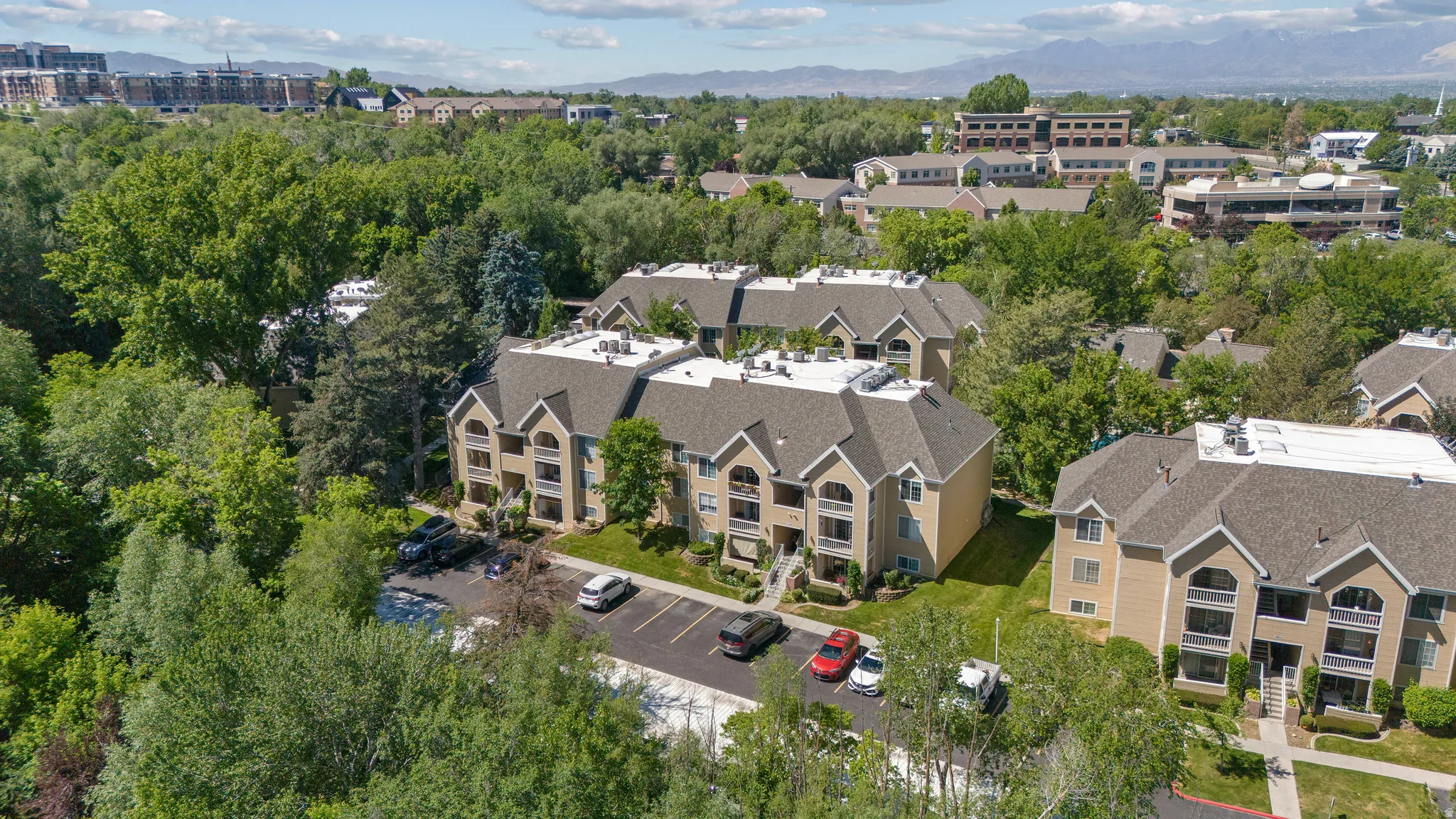 Multi-story condominium buildings featuring light-colored siding, dark shingled roofs, and arched window details