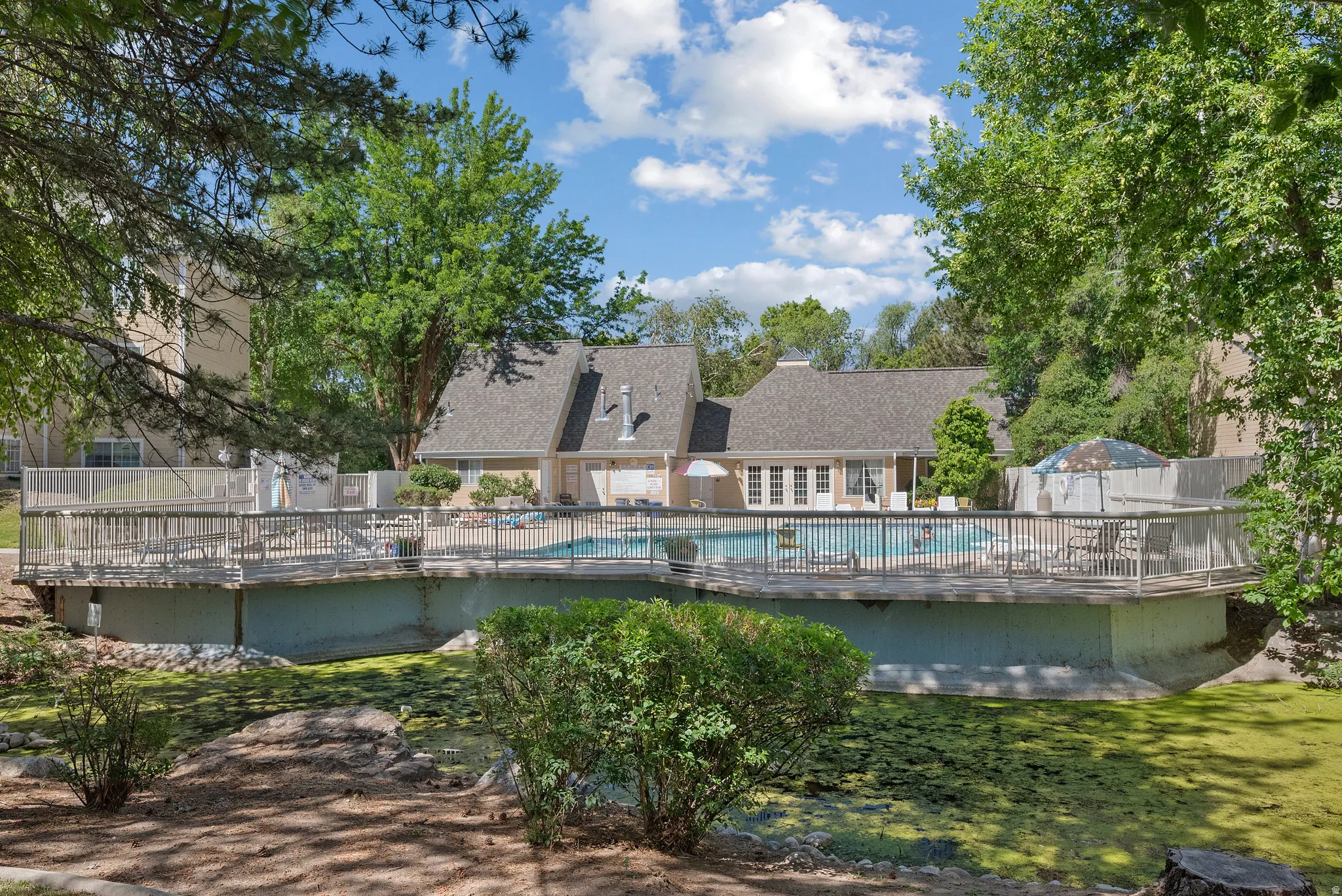 Expansive outdoor pool area featuring a surrounding wooden deck with metal railings