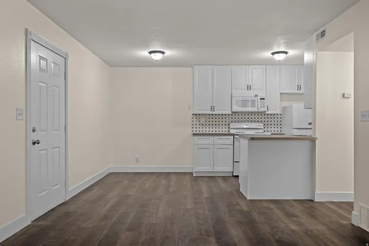 Kitchenette with white cabinetry, built-in microwave, electric range, and a two-tier peninsula