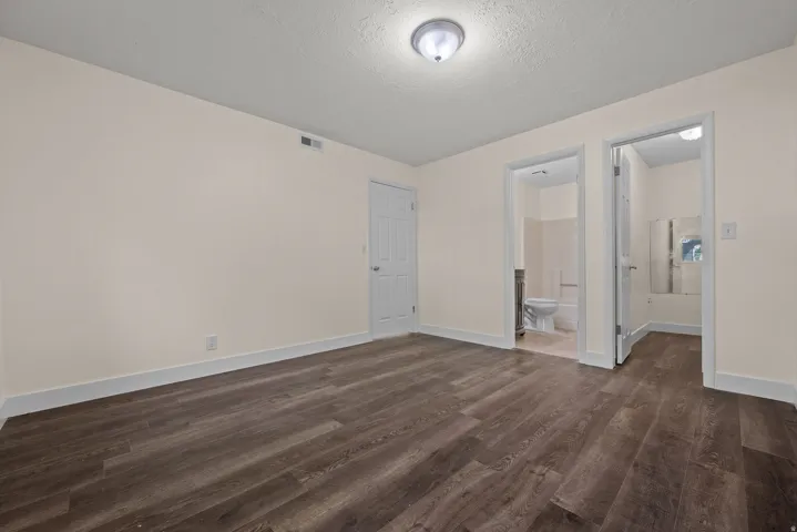 Spacious room featuring wood-finish flooring, light-toned walls, white trim, and a flush mount ceiling light
