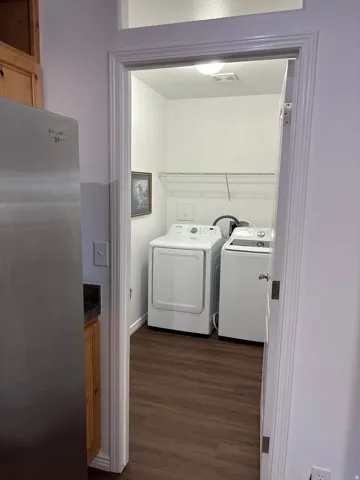 Dedicated laundry area featuring wood-finish flooring, white walls, and an overhead light fixture