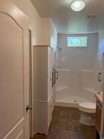 Bathroom featuring a walk-in shower with dual built-in benches, a transom window, and grab bars