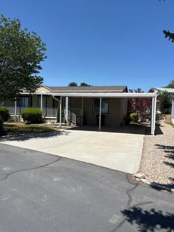 Property exterior featuring a covered carport, concrete driveway, and a front porch with white railings