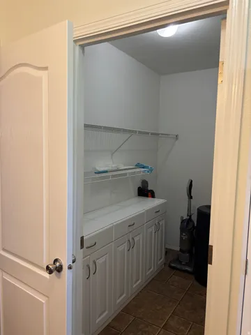 Utility space featuring white cabinetry, tile countertop, and wire shelving