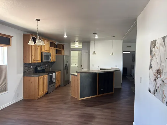 Kitchen featuring wood cabinetry, stainless steel appliances, dark countertops, and a coordinating backsplash