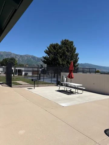 Outdoor patio area featuring a concrete surface, a picnic table, and an umbrella