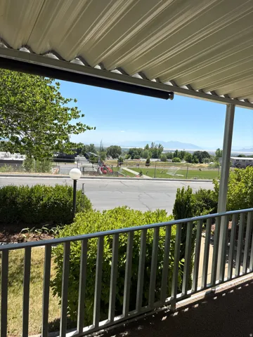 Covered patio featuring a metal railing and distant mountain scenery