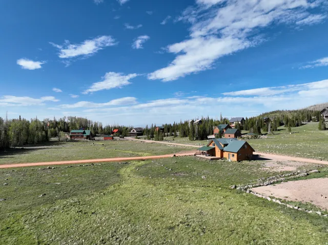 Expansive grassy terrain featuring a dirt road and scattered residences