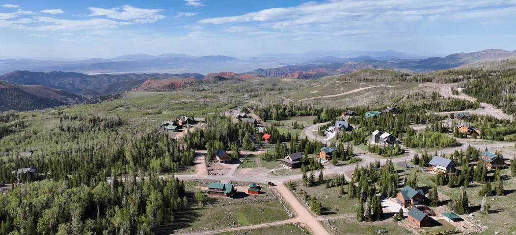Mountain community featuring numerous cabins and residences amidst a forested landscape