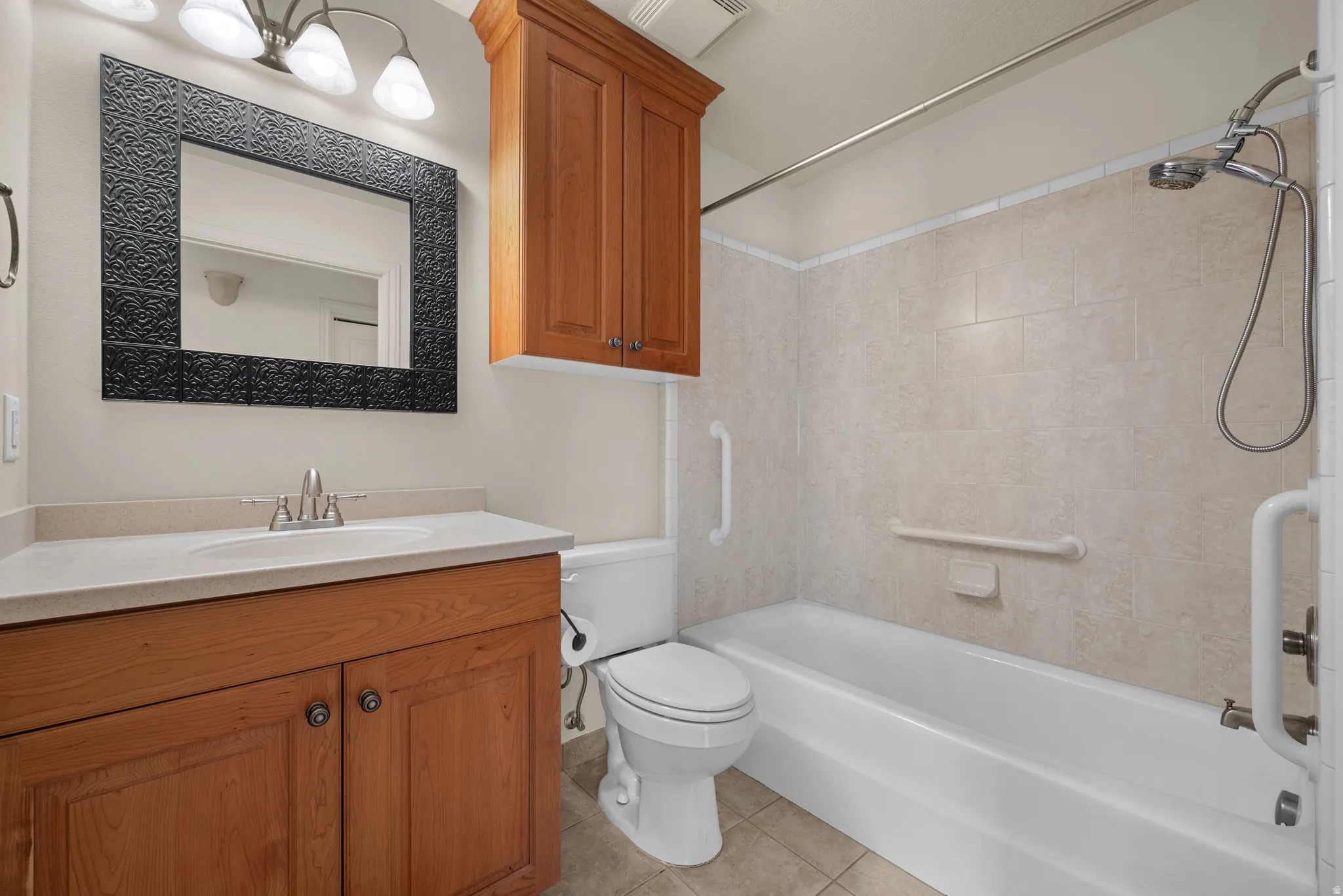 Bathroom featuring a wood-finish vanity with a light-toned countertop, an integrated sink, and a framed mirror