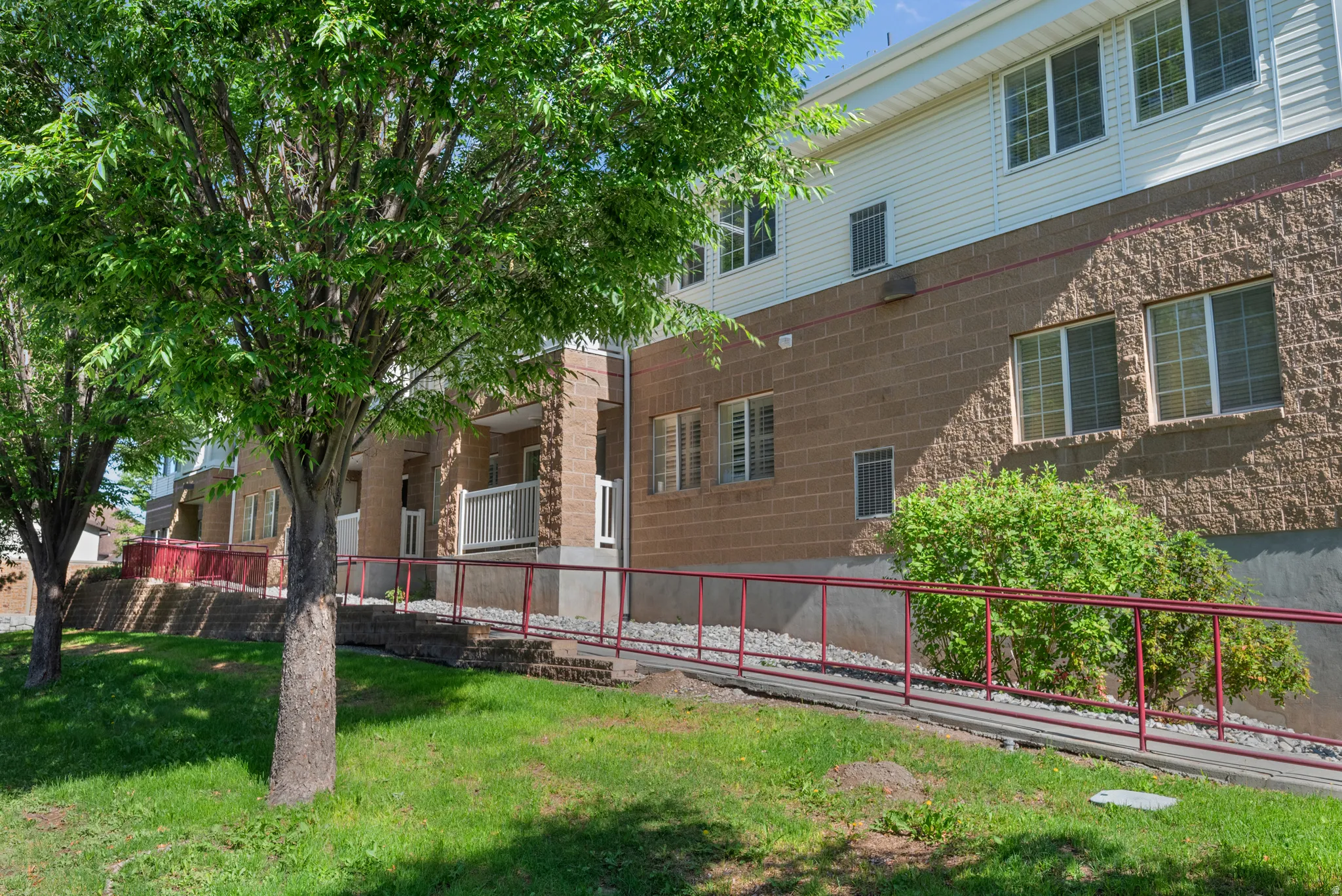 Multi-level building with a brown block facade and white siding upper levels