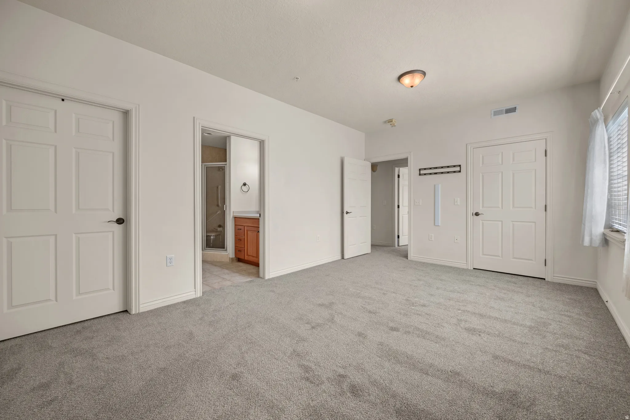 Spacious room featuring light gray carpeting and white walls