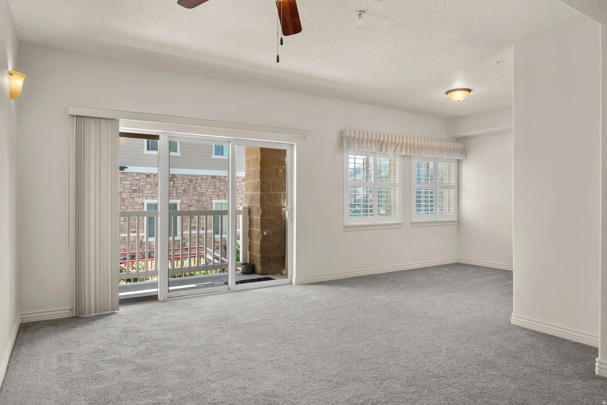 Spacious living area featuring light gray carpeting and white walls