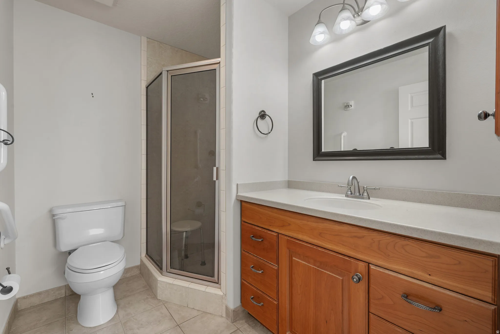 Bathroom featuring a corner shower with a glass enclosure, wood-finish vanity with a light-colored countertop, and a framed mirror