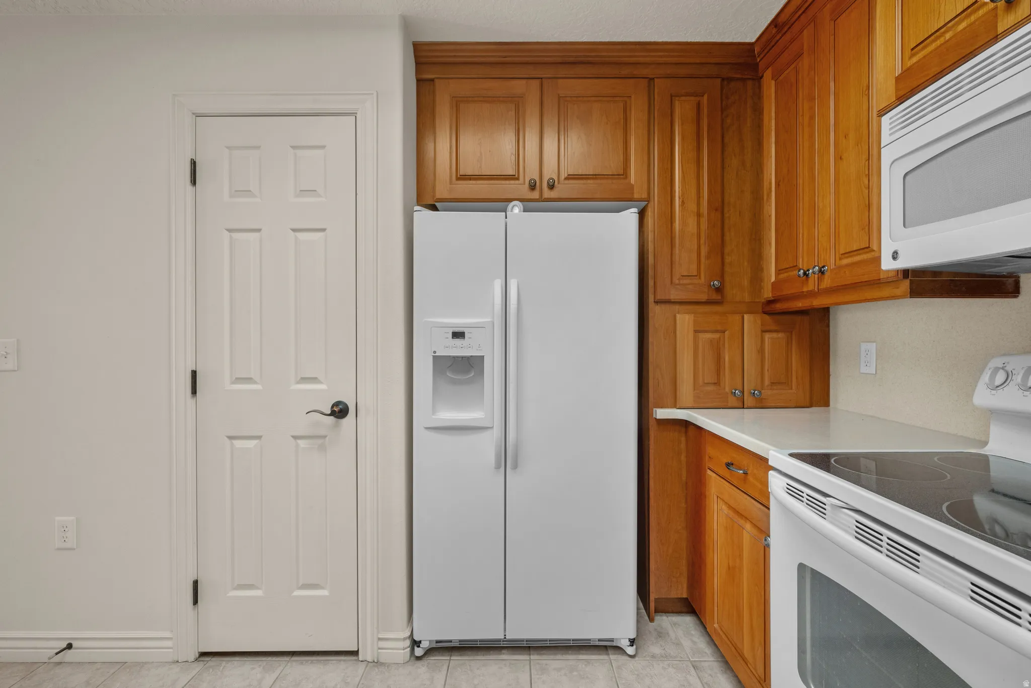 Kitchen area featuring wood cabinetry, a built-in microwave, white electric range, and a white side-by-side refrigerator