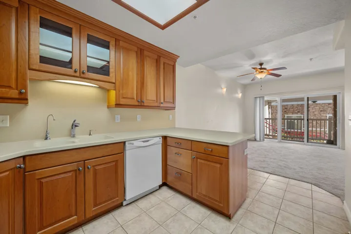 Kitchen featuring warm wood cabinetry, light-toned countertops, tile flooring, and a skylight