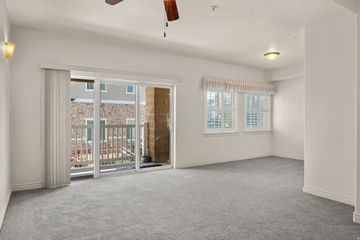Spacious living area featuring light gray carpeting and white walls