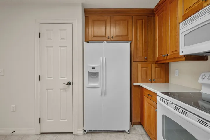 Kitchen area featuring wood cabinetry, a built-in microwave, white electric range, and a white side-by-side refrigerator