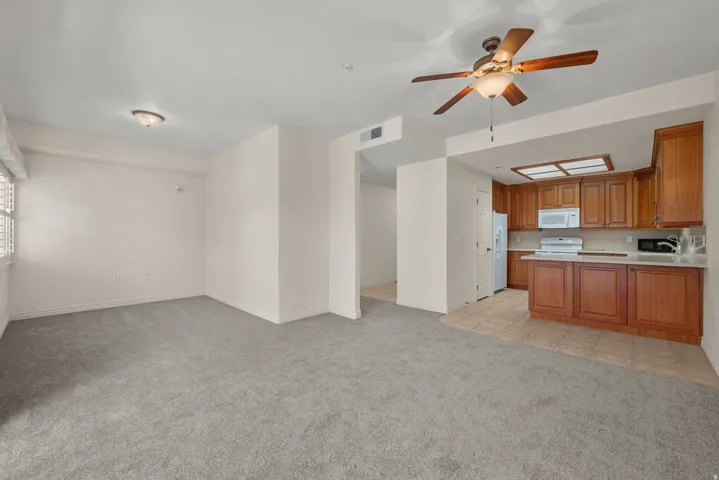 Open-concept living space featuring neutral gray carpeting and white walls