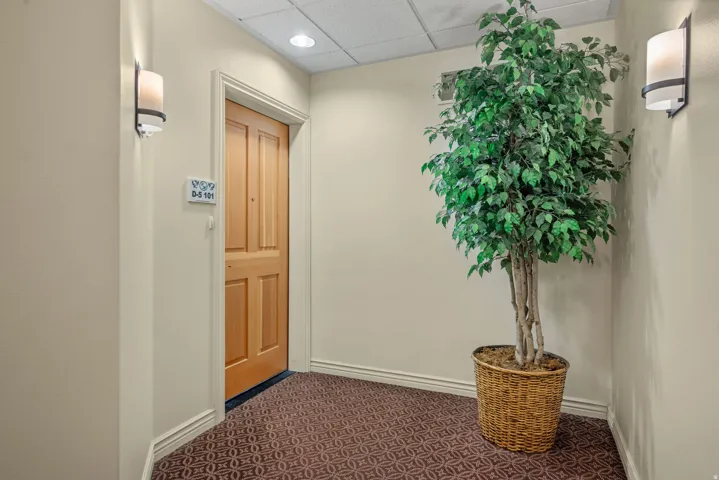 Entryway featuring a paneled wood door, sconce lighting, and patterned carpet flooring