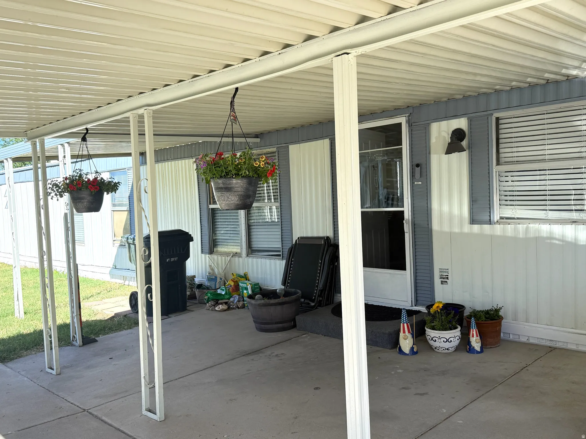 Covered concrete patio with white support columns and corrugated metal roofing