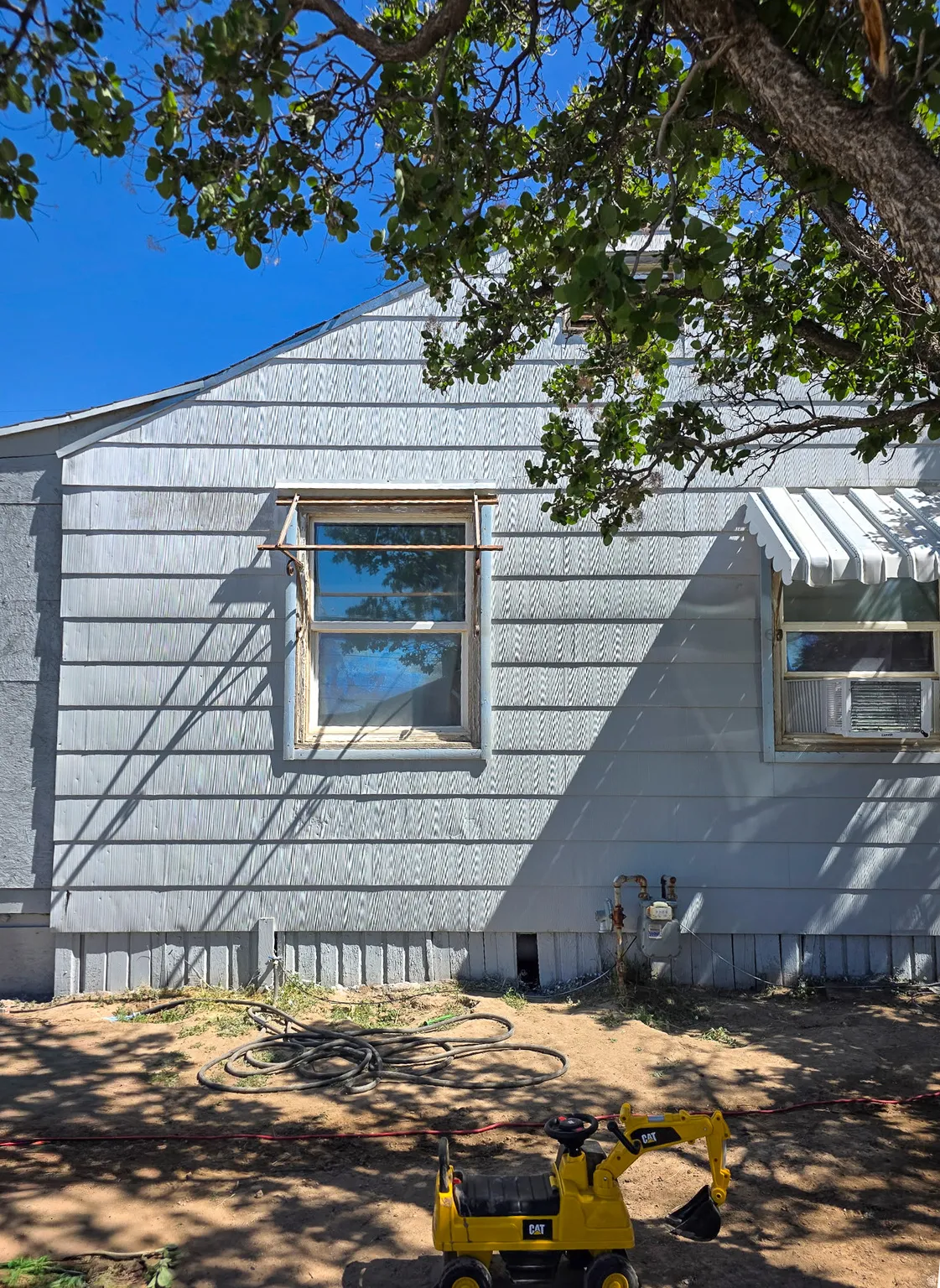 Light blue horizontal siding exterior featuring a white window awning and a foundation with vertical paneling