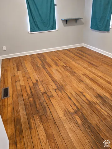 Hardwood plank flooring with white trim, light gray painted walls, and a wall-mounted shelving unit