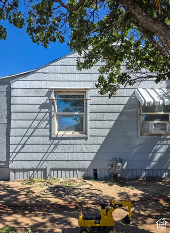 Light blue horizontal siding exterior featuring a white window awning and a foundation with vertical paneling