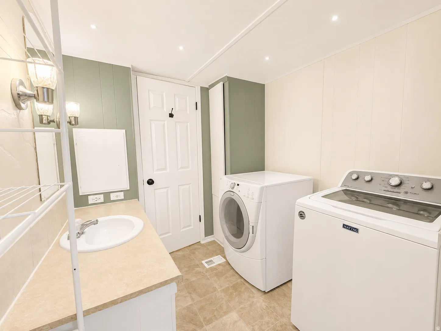 Combined bathroom and laundry room featuring washer and dryer, vanity, updated lighting, and convenient built-in storage.