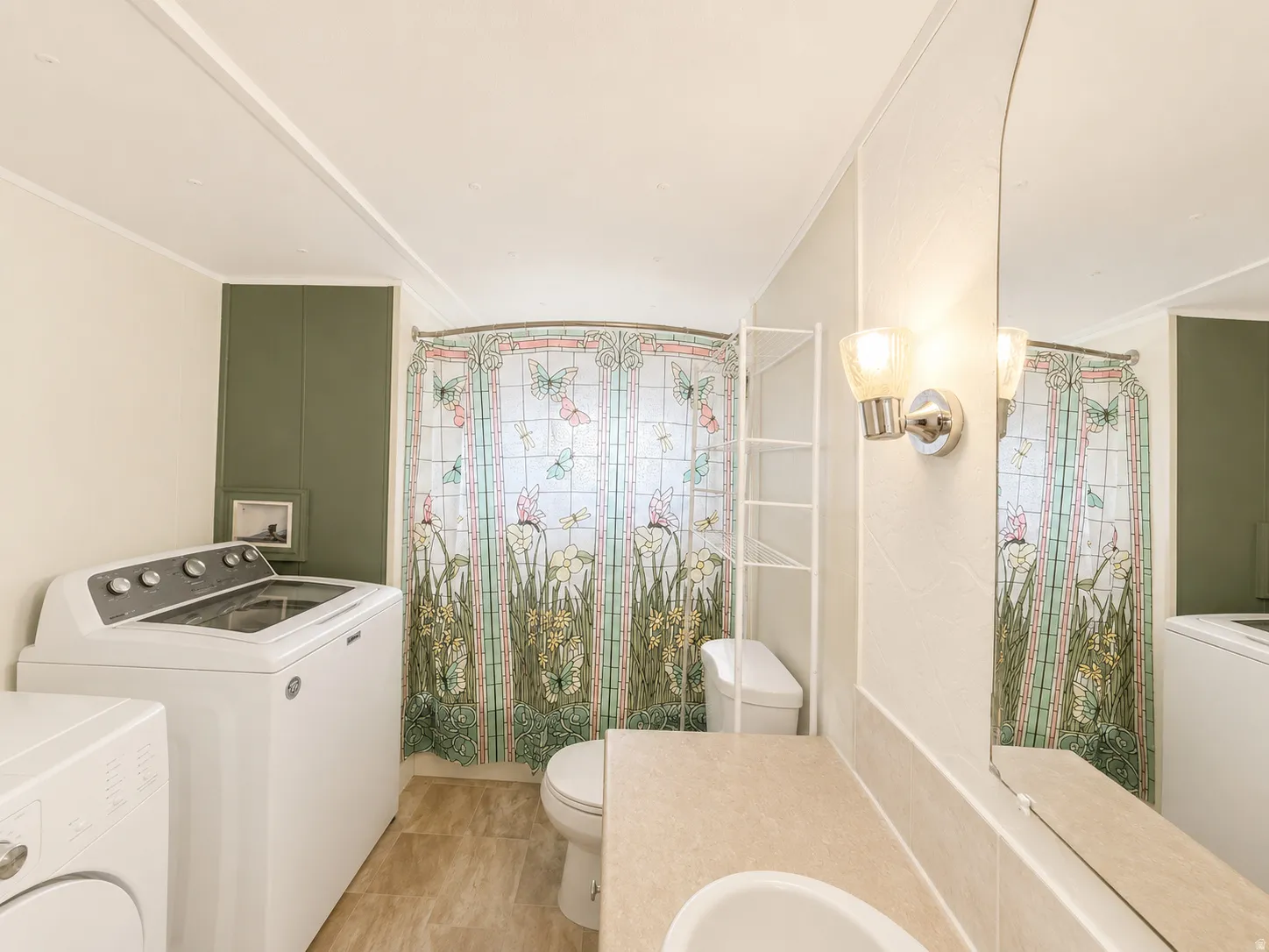 Full bathroom with tub/shower combination, vanity, large mirror, and laundry area.