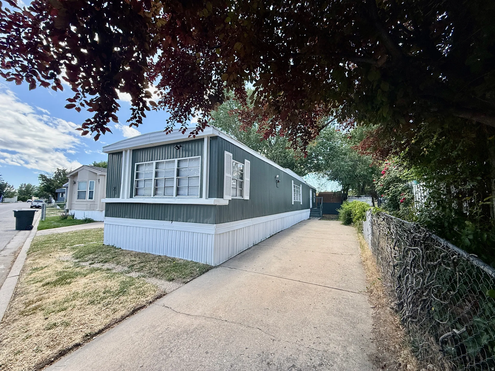 Front exterior with extended driveway parking, mature landscaping, and classic white trim accents.