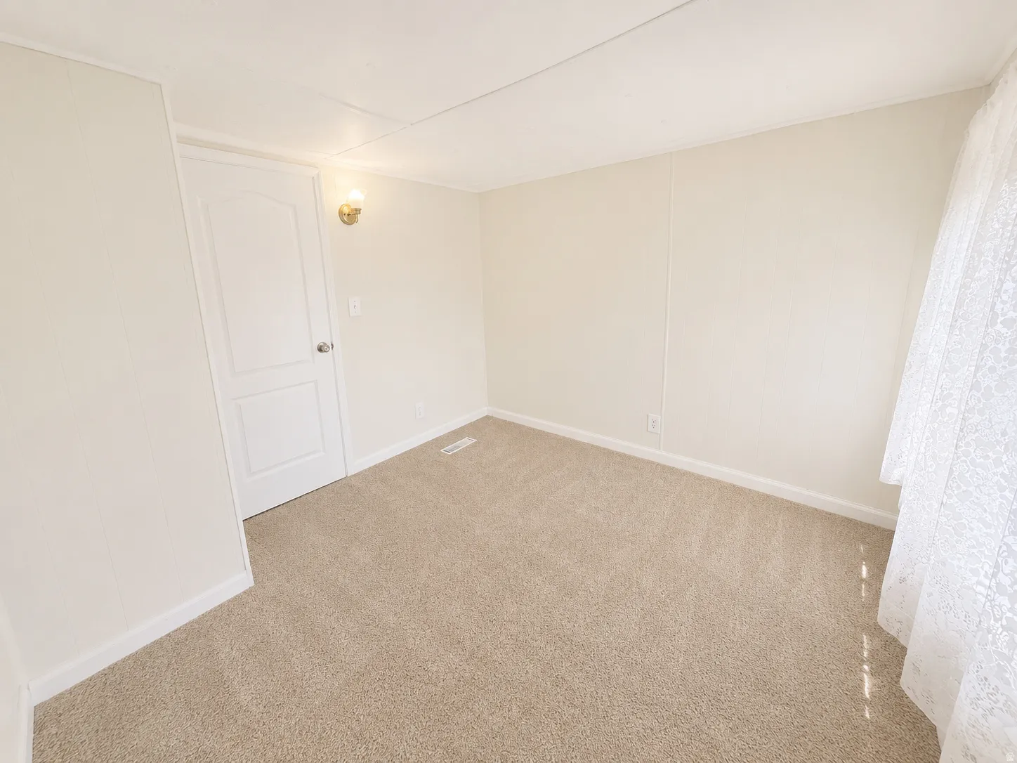 Secondary bedroom with neutral finishes, soft carpet, and natural light from the window.