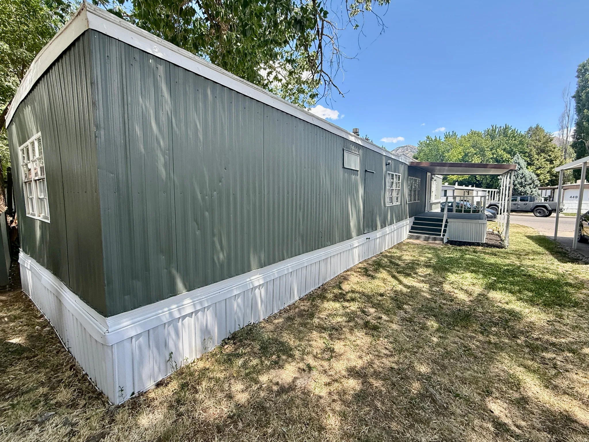 Back side exterior view featuring mature shade trees, lawn area, and easy access to the covered entry.
